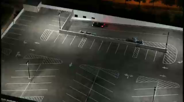 A ground-level nighttime shot of a parking lot with vehicles illuminated by tall light poles during an HTX Corvettes meet. A ground-level nighttime shot of a parking lot with vehicles illuminated by tall light poles during an HTX Corvettes meet.